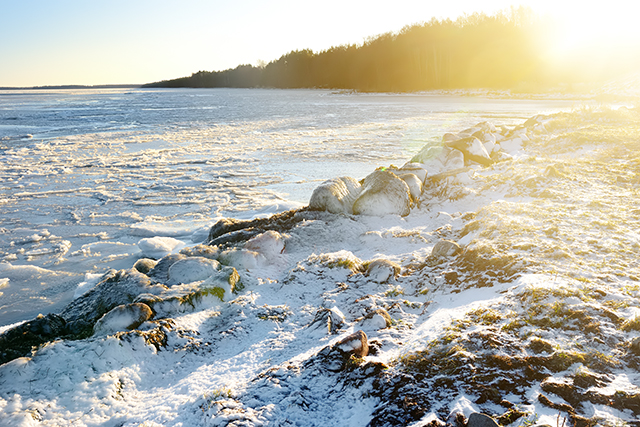 Jäätynyt Itämeren lahti ja kevyen lumikerroksen peittämiä rantakallioita.