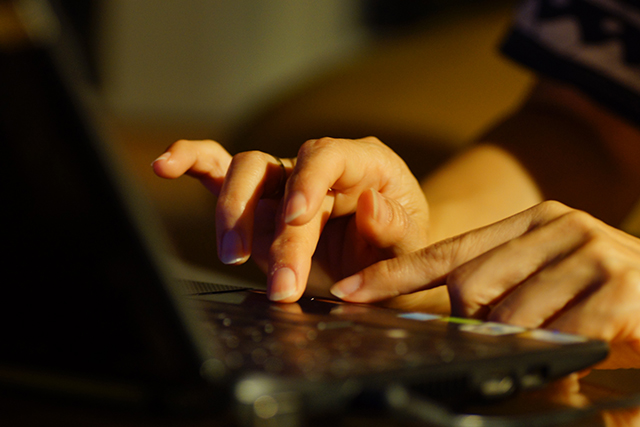 Kädet kannettavan tietokoneen näppäimistöllä