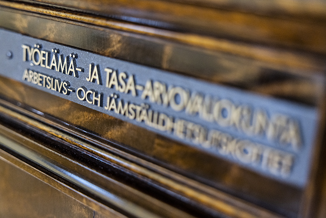 Työelämä- ja tasa-arvovaliokunnan kokoushuoneen ovikyltti Eduskuntatalossa. Kyltissä valiokunnan nimi suomeksi ja ruotsiksi.