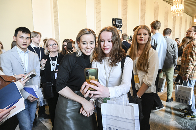 Valokuva, jossa on paljon nuoria. Kuvassa etualalla on kansaedustaja Sofia Virta ja nuori, jotka ottavat yhteiskuvaa.