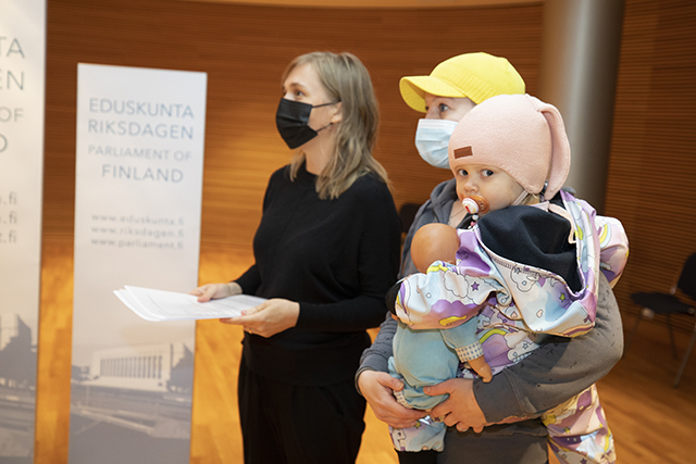 Kansalaisaloitteen luovuttajat eduskunnan Pikkuparlamentin Kansalaisinfossa. Kaksivuotias Nina Lintula äitinsä sylissä.