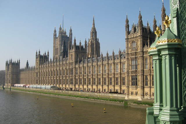 Britannian parlamenttitalo ulkoa kuvattuna, kuvan etualalla Thames-joki.