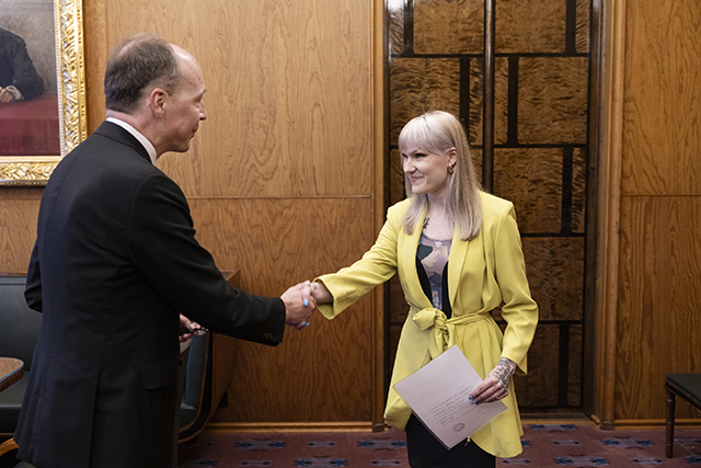 Puhemies Halla-aho ja Jessi Jokelainen kättelevät. puhemiehellä musta puku, jokelaisella keltainen takki